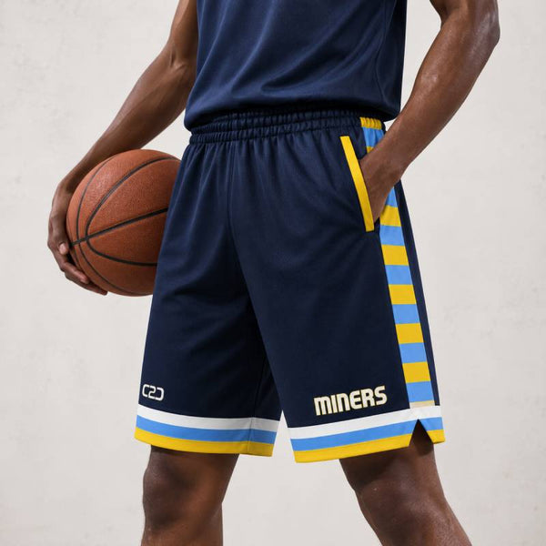 A person wearing navy Miners Core Shorts Pro with yellow and light blue side stripes and “MINERS” branding, shown on a light neutral background. No side seam design, above-knee fit, breathable moisture-wicking fabric, and customisable team shorts.